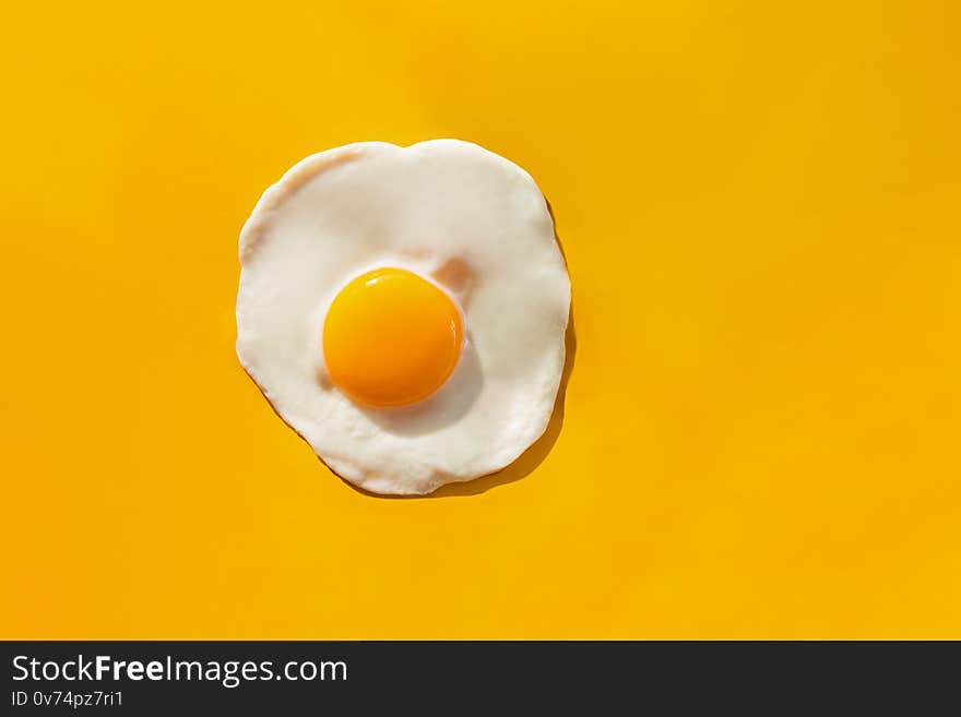 Fried egg on yellow background, top view