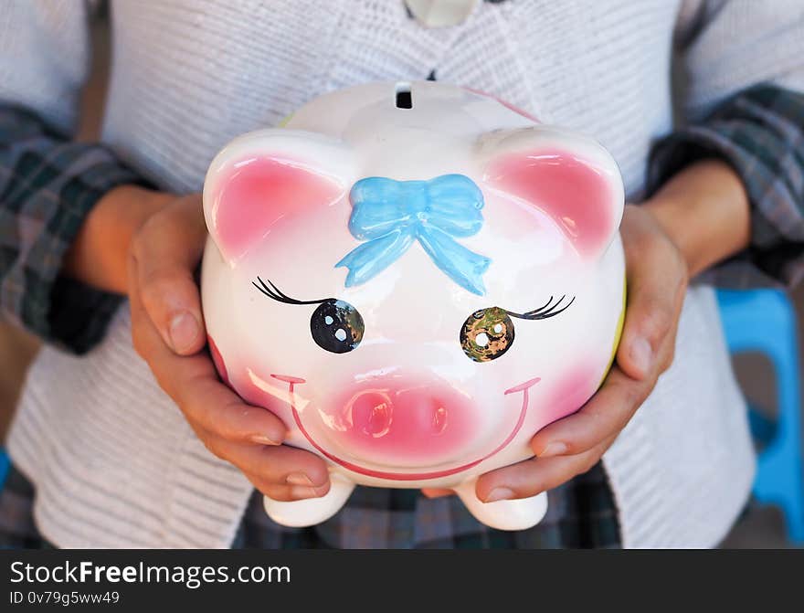 Young woman with a piggy bank on a pink background