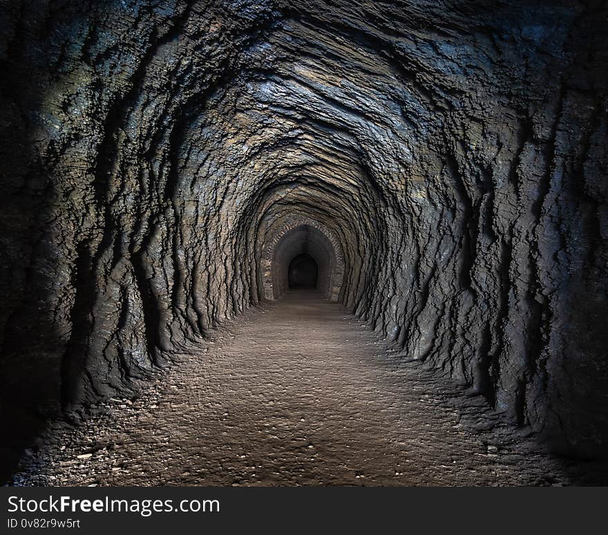 Gravel path through an abandoned railway tunnel showing rock formations, Otago, New Zealand. Gravel path through an abandoned railway tunnel showing rock formations, Otago, New Zealand