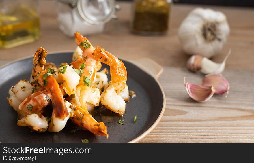 Delicious seafood. Homemade prawns with garlic sauce on a black plate. Delicious seafood. Homemade prawns with garlic sauce on a black plate