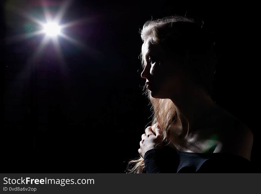 Portrait of a girl illuminated by the contour light of a flash on a black dsrk background