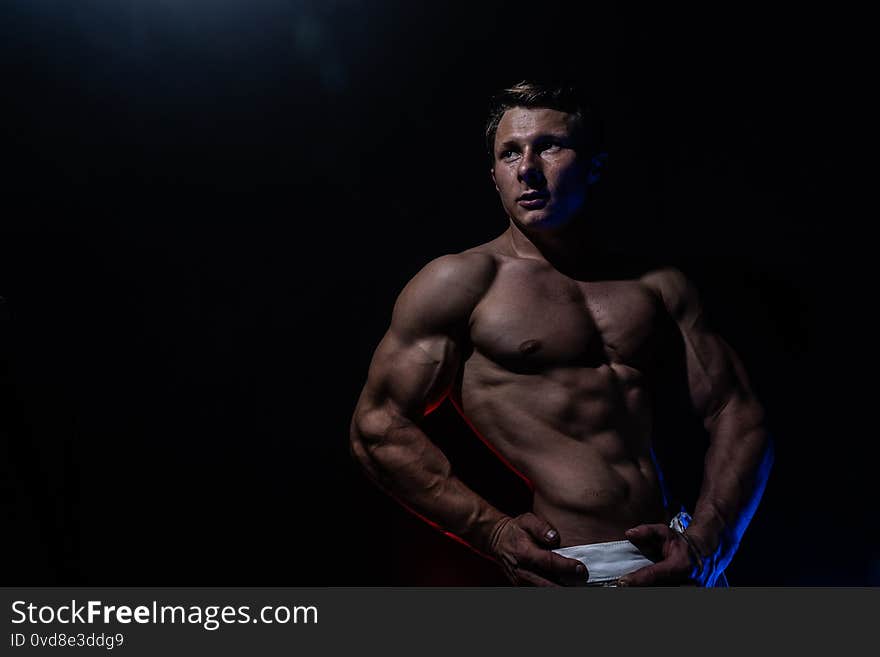 Muscular man showing muscles isolated on the black background. Concept of healthy lifestyle and healthcare.