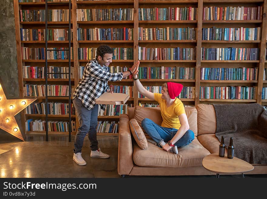 High five. Dark-haired men in a checkered giving high five to his friend. High five. Dark-haired men in a checkered giving high five to his friend