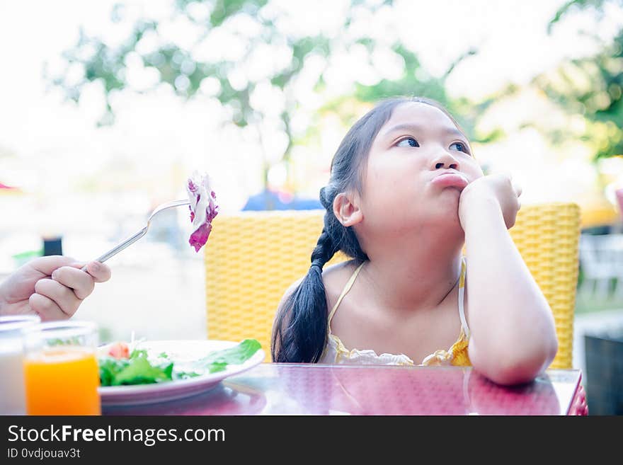 Asian child girl with expression of disgust against vegetables in salad, Refusing food concept