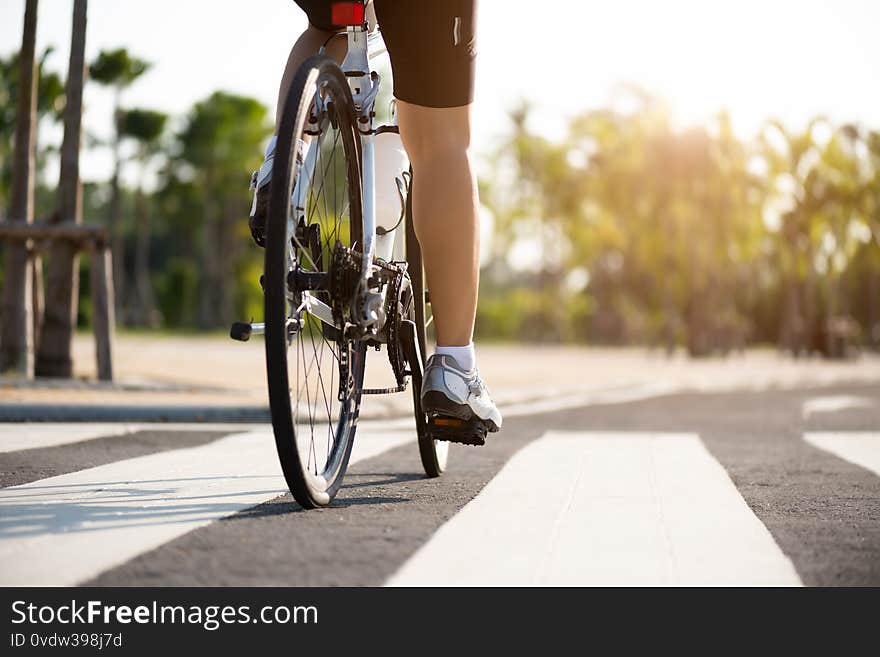 Athlete woman cyclist legs riding Mountain Bike on the road in the morning