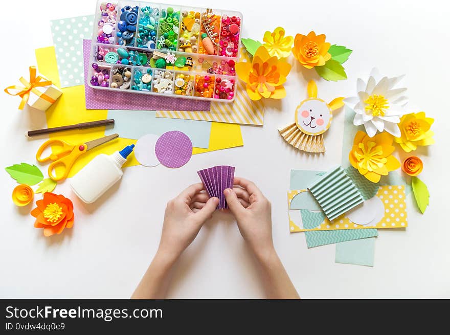 Child makes an Easter Bunny craft. Beads and material for creativity. Kindergarten and school. White background