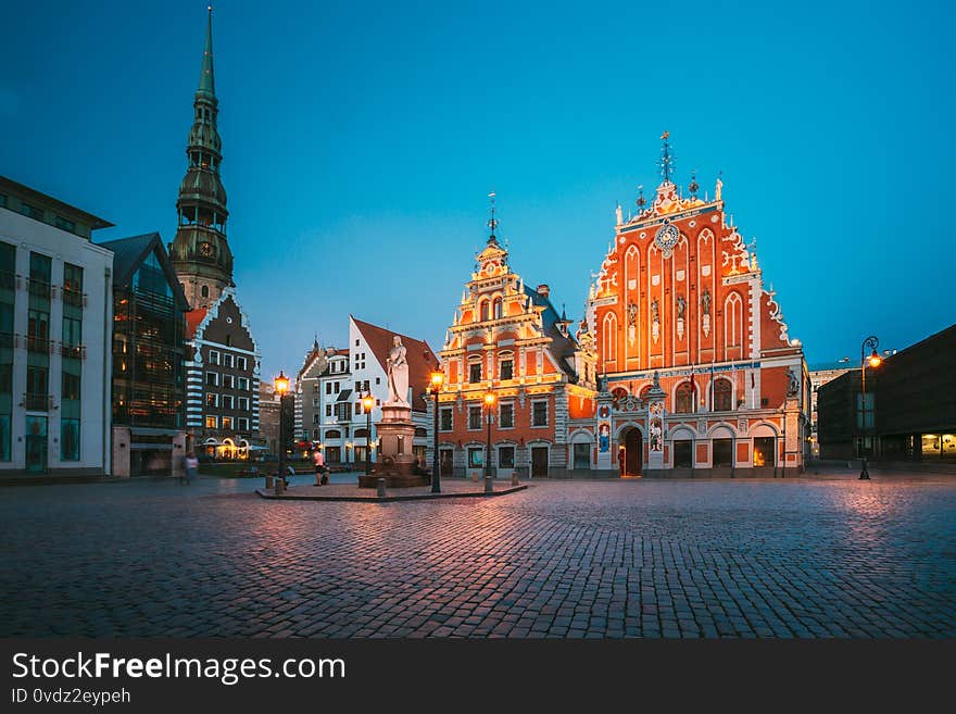 Riga, Latvia. Scenic Town Hall Square With St. Peter`s Church, Schwabe House, House Of Blackheads. Popular Showplace With Famous Landmarks On It In Bright Evening Illumination In Summer Twilight Under Blue Sky.
