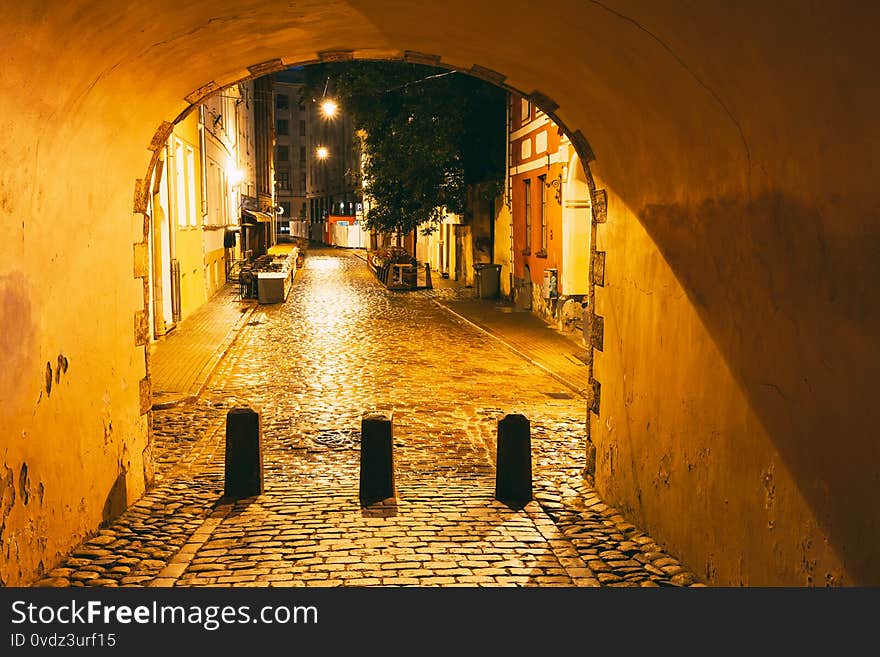 Riga, Latvia. Swedish Gate Gates Is A Famous Landmark. Old Arch Of Swedish Gate In Original State On Troksnu Street In Old Town. Cultural Monument In Lighting At Night Illumination. Riga, Latvia. Swedish Gate Gates Is A Famous Landmark. Old Arch Of Swedish Gate In Original State On Troksnu Street In Old Town. Cultural Monument In Lighting At Night Illumination