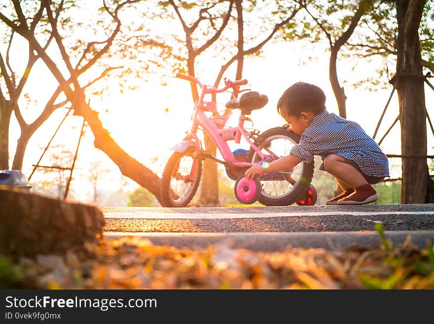 1-2 year asian baby boy playing with bicycle on bike road in park sunset light