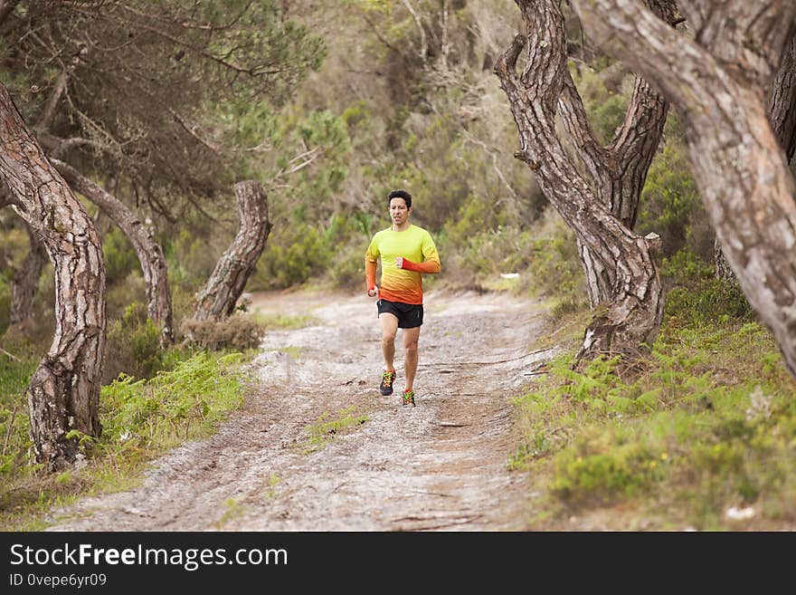 Mature man running at the park between trees