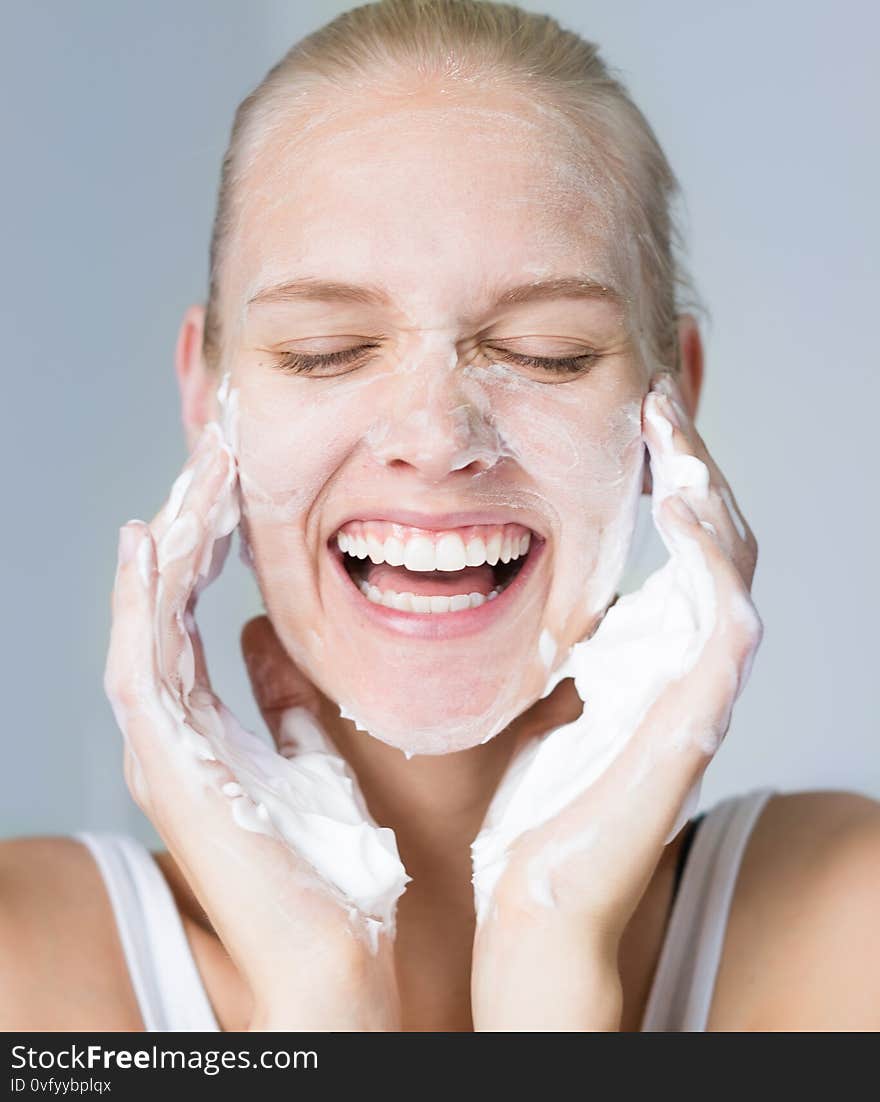 A female model splashing her face with water and soap in the bathroom. Beauty care and hygiene concept. A female model splashing her face with water and soap in the bathroom. Beauty care and hygiene concept