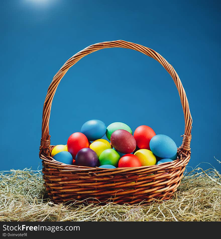 Easter basket with multicolor eggs, blue background, close-up view