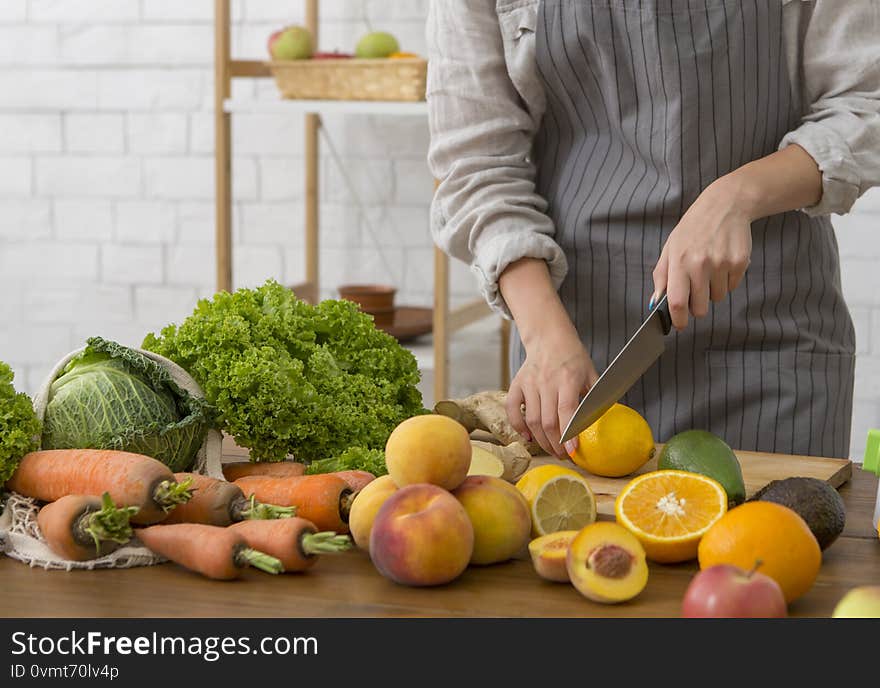 Vegan meal and detox concept. Unrecognizable woman cutting fresh fruits and vegetables for cooking smoothie, copy space