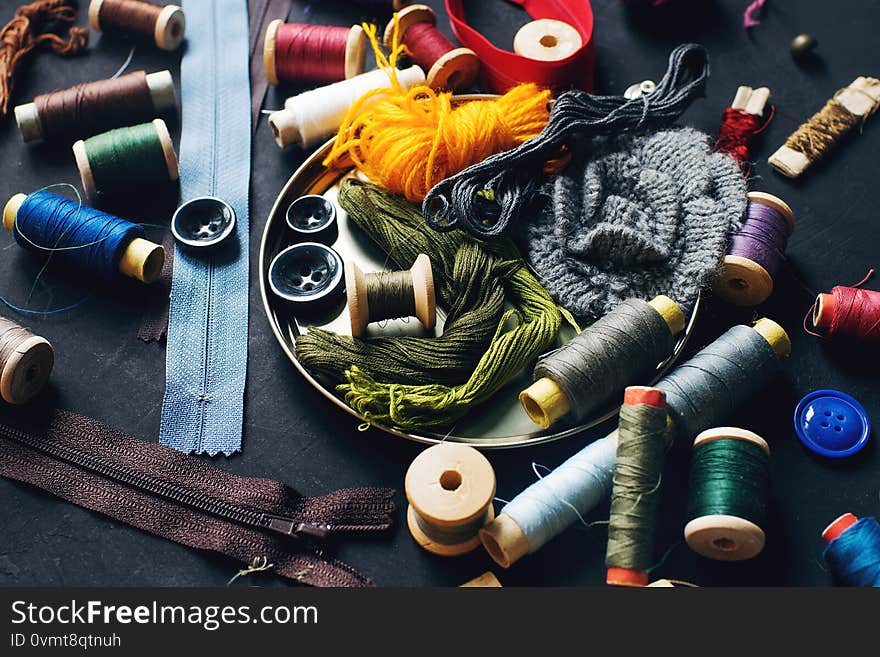 Sewing kit accessories for handicraft or needlework on dark stone table, colorful threads, home hobby and quarantine concept,  selective focus