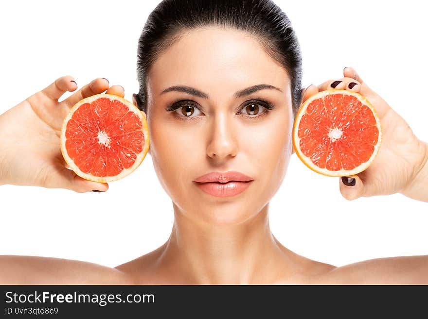 Beautiful young woman holding piece of grapefruit close to face, isolated over white background