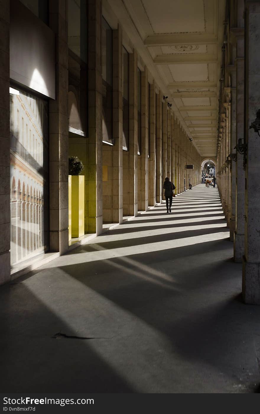 Corridor made up of lights and shadows from the architectural columns that make it up while a person walks through it