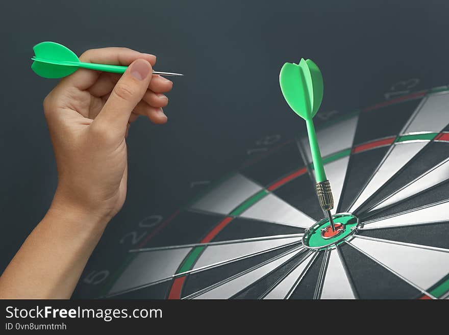 Woman with darts and board on background, closeup