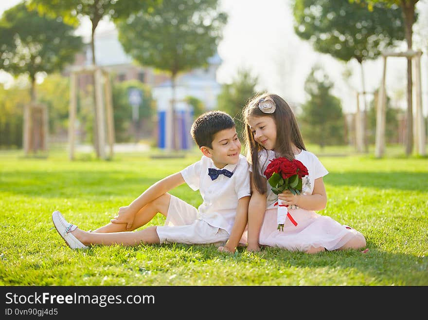 Two beautiful baby brother and sister sitting in the Park in the summer on the grass. The concept of family and family entertainment