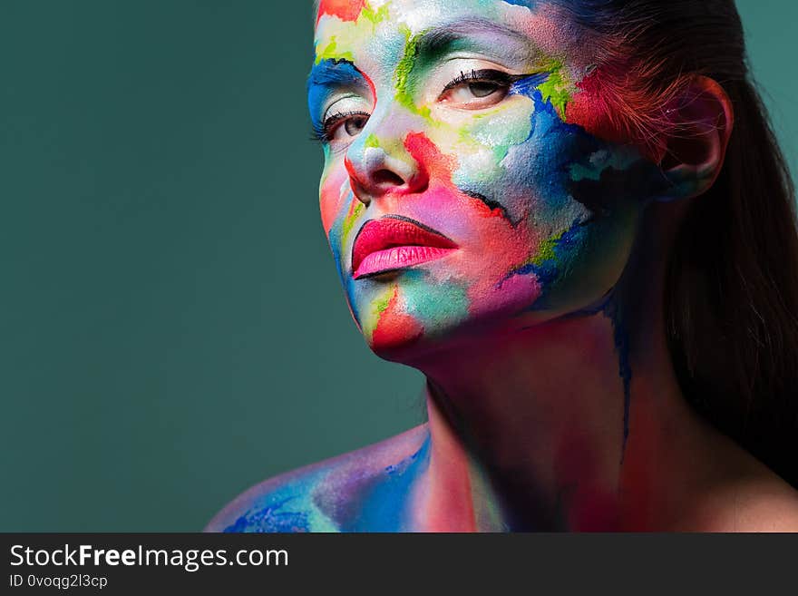 Fashion and creative makeup, young beautiful woman abstract face art, portrait on a turquoise background.