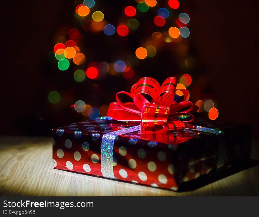 Gift box in the circle of light against the background of multicolored lights. Gift box in the circle of light against the background of multicolored lights