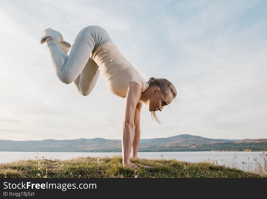 A beautiful woman, a fitness instructor, in light clothing, trains on the beach, against the sky. Shows exercises from yoga, Pilates, Deep Work, Step aerobics. A beautiful woman, a fitness instructor, in light clothing, trains on the beach, against the sky. Shows exercises from yoga, Pilates, Deep Work, Step aerobics