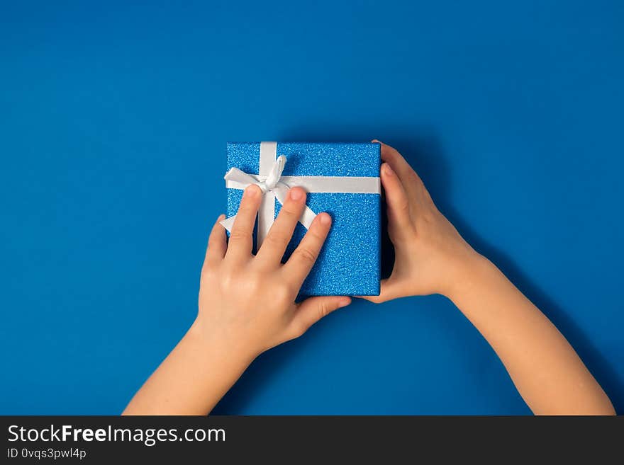 Children`s hands hold a blue shiny box