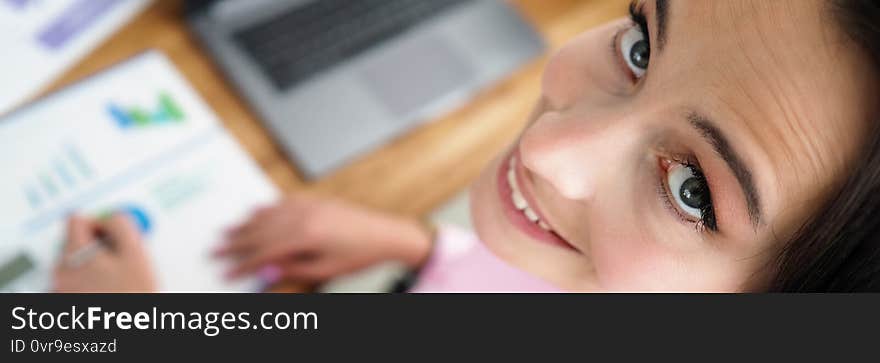 Woman is sitting office with reports and smiling