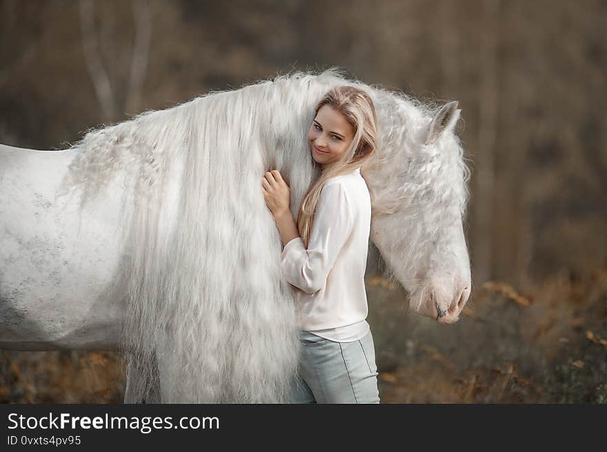 Beautiful young woman with white tinker cob in an autumn field