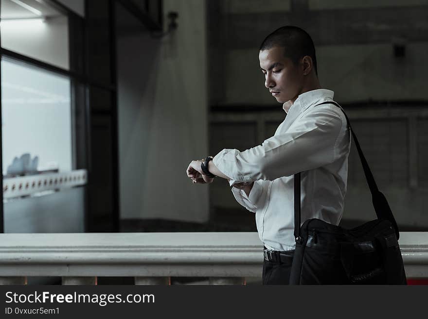 Thai man looking at his watch to check the time. Thai man looking at his watch to check the time