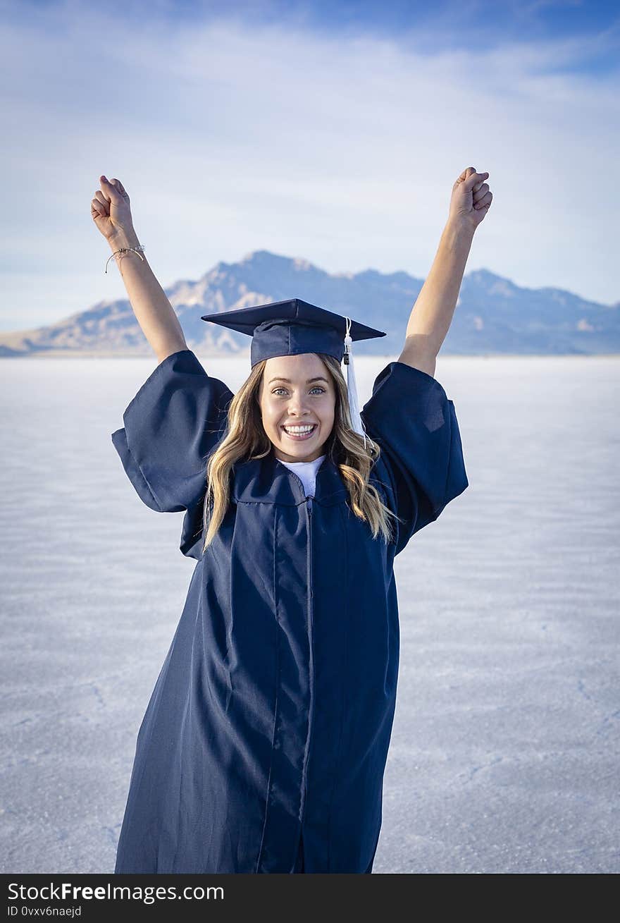 Cute Young woman in her graduation cap and gown showing excitement after graduating