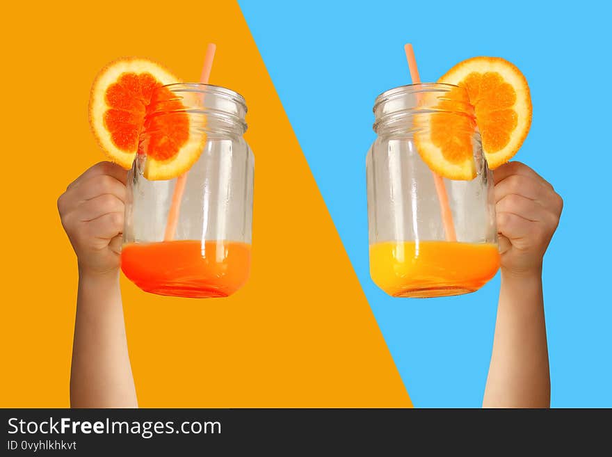 Two children are holding a glass jar in their outstretched arms with orange juice from an orange or lemon with a straw, the concept of a healthy diet, vitamins, lifestyle