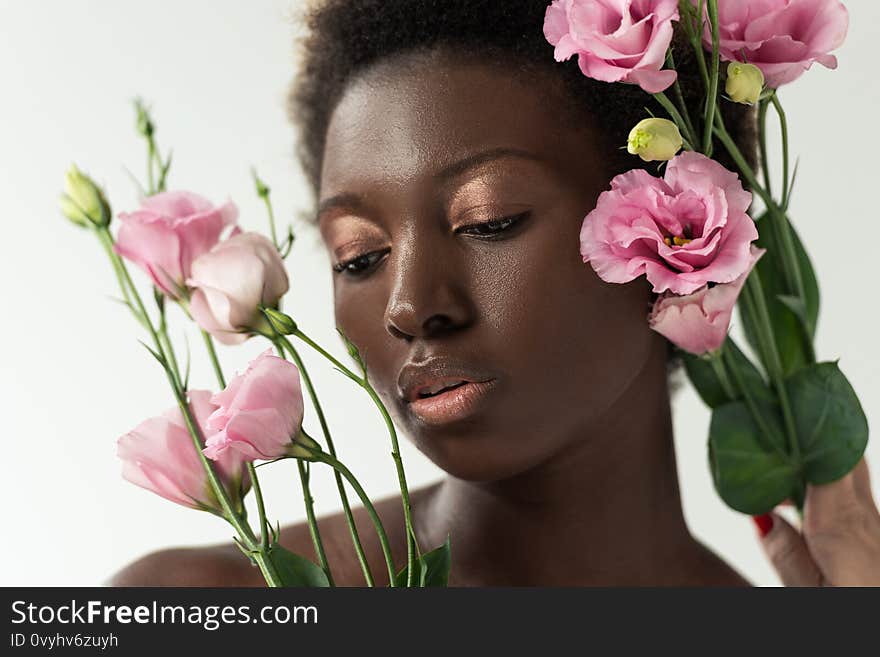 Tender naked african american girl with pink flowers isolated on white