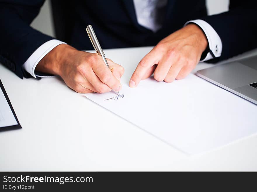 Businessman sitting at office desk signing contract.