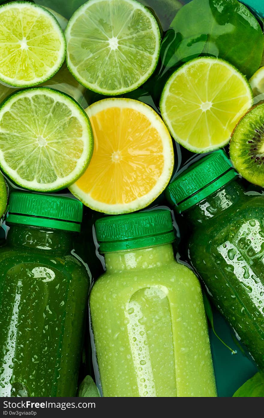 Close-up of fresh chilled green detox-smoothies surrounded by slices of lemon, lime, kiwi and spinach leaves. diet concept, good nutrition, citrus, vegetarian background. Close-up of fresh chilled green detox-smoothies surrounded by slices of lemon, lime, kiwi and spinach leaves. diet concept, good nutrition, citrus, vegetarian background