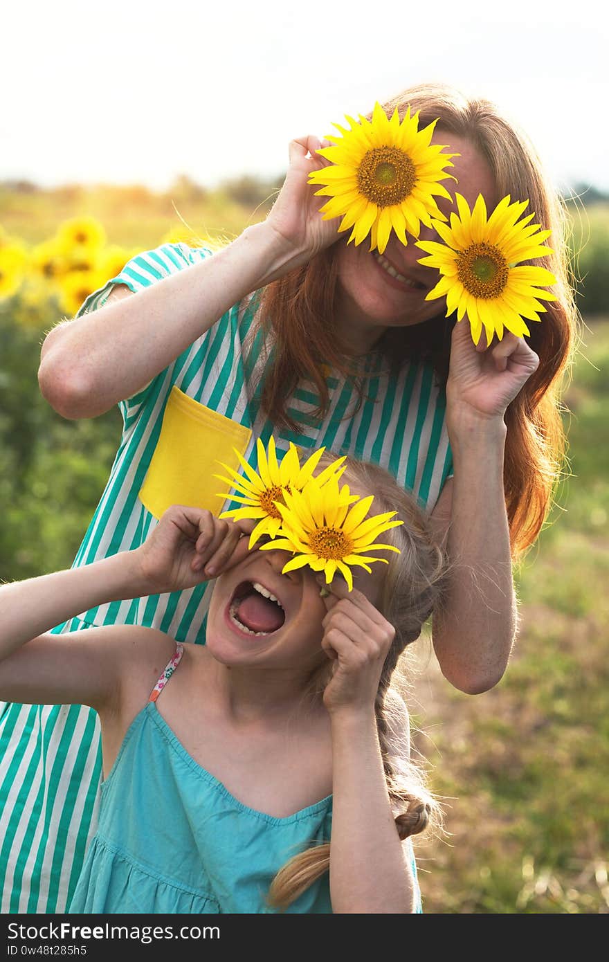 Crazy happy girls in a field of sunflowers at sunset. family - mom and daughter. Ukraine. Crazy happy girls in a field of sunflowers at sunset. family - mom and daughter. Ukraine