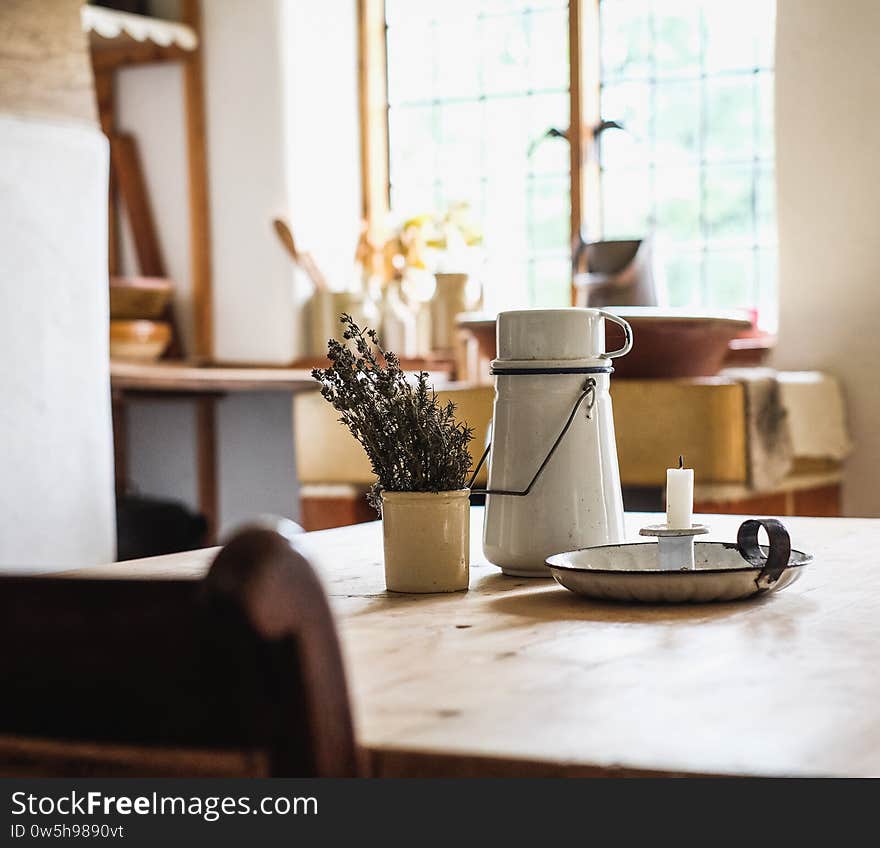 Candle, thermos and a bowl of plants put on the table in the kitchen