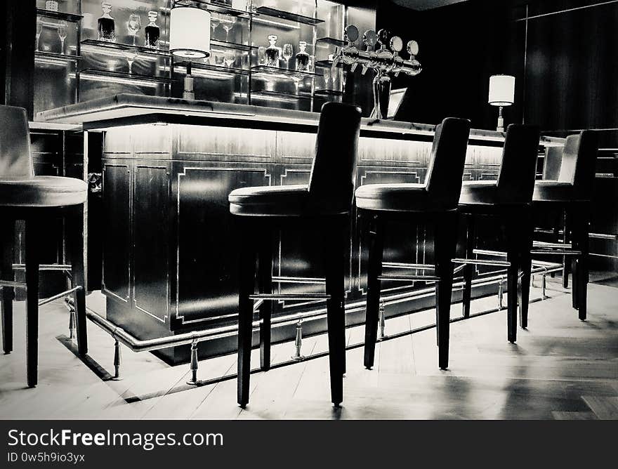 Amazing grayscale shot of a bar counter with elegant chairs and relaxing atmosphere