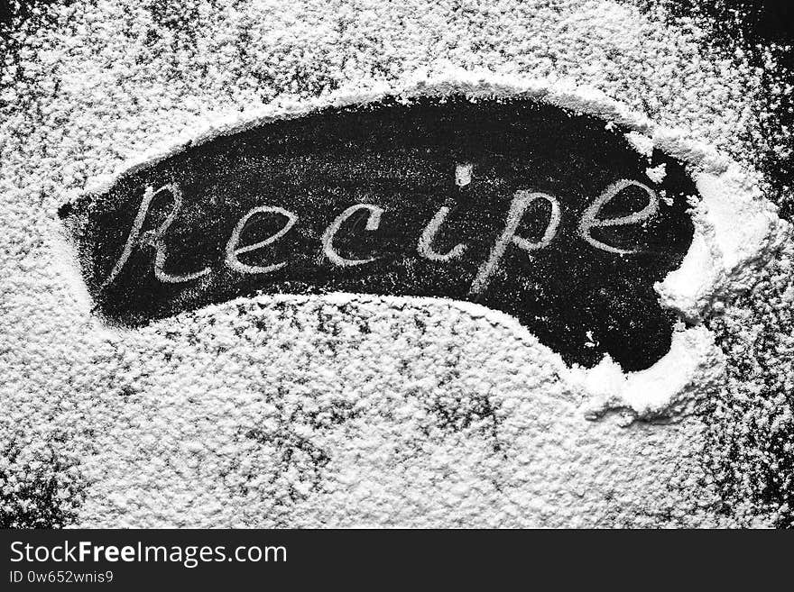 Headline recipe sprinkle flour on a black table. Banner recipe handwritten word