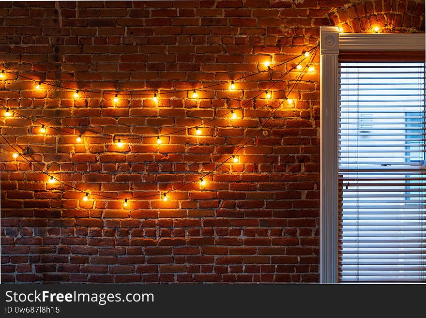 The string of vintage lights bulbs inside at night, lights on a brick wall background, selective focus