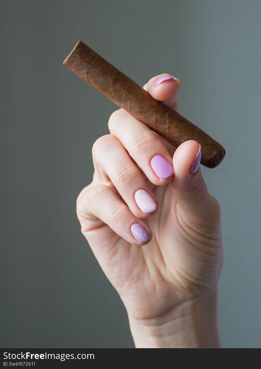 Cigar in woman hand, photo on gray background