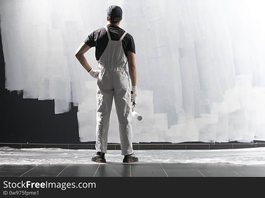 Male decorator painting a wall with white color