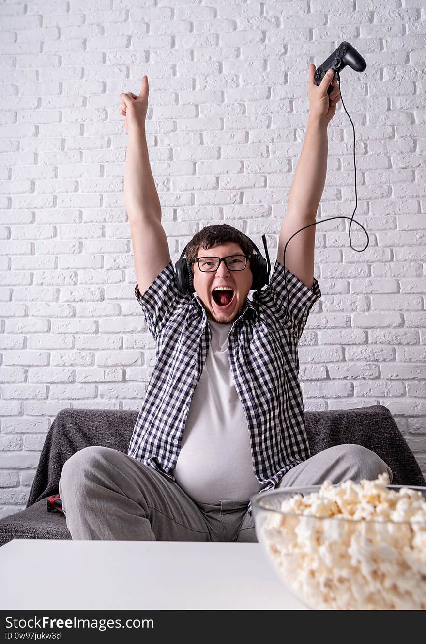 Excited young man playing video games at home enjoying his victory