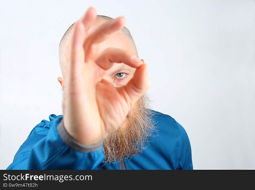 The portrait of a man with a beard looking through his fingers
