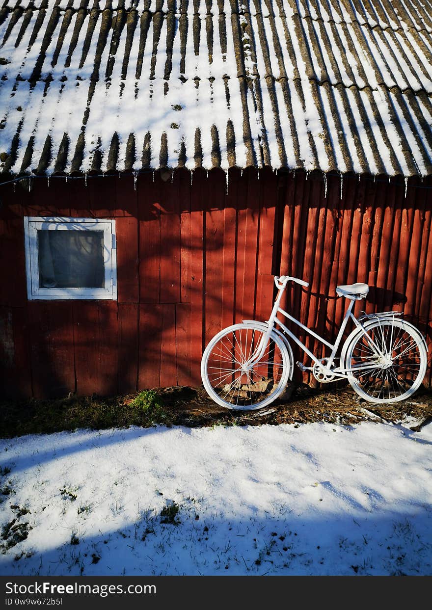 Decorative old painted in white bicycle near farm barn