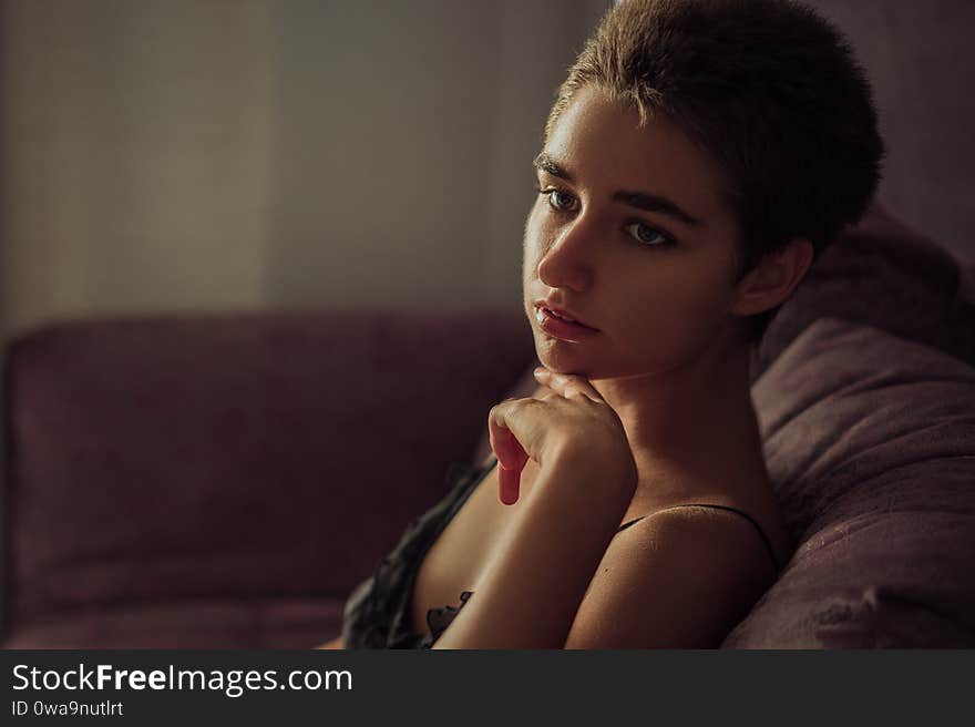 Young cute woman sitting in a chair sad, short hair.