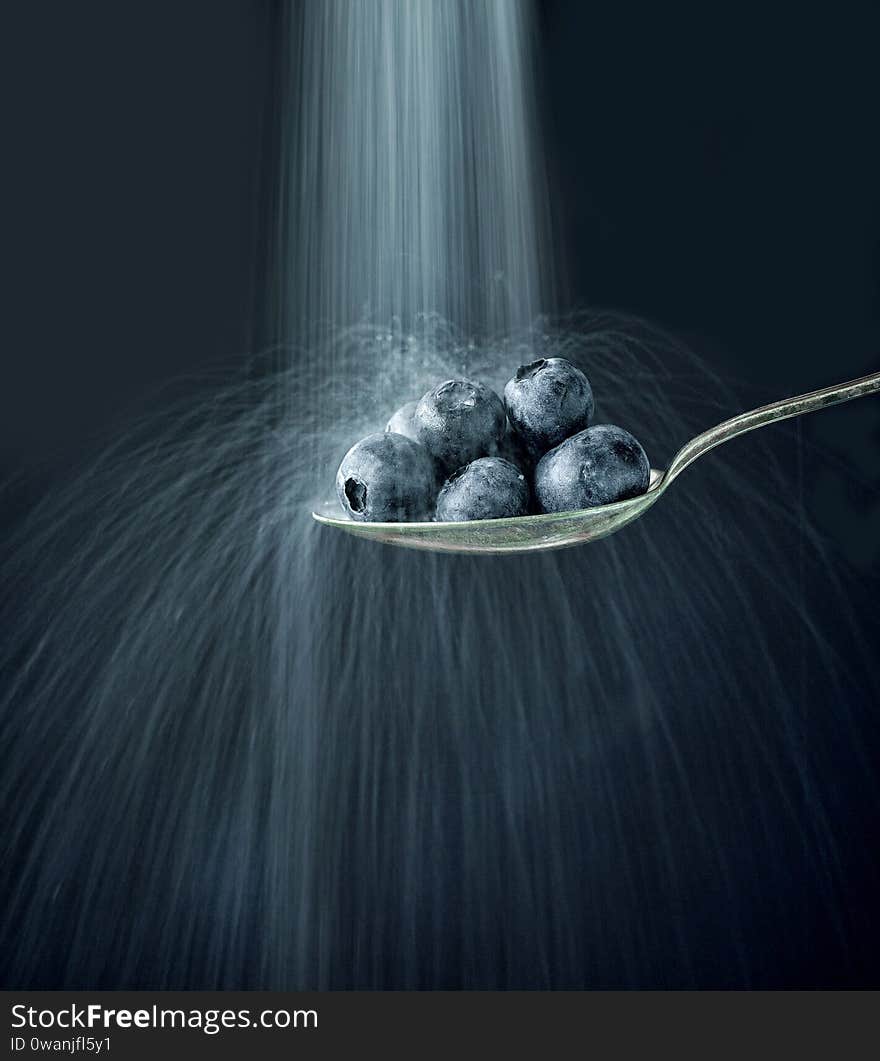 Sugar falls on blueberries, selective focus, black background. Sugar falls on blueberries, selective focus, black background