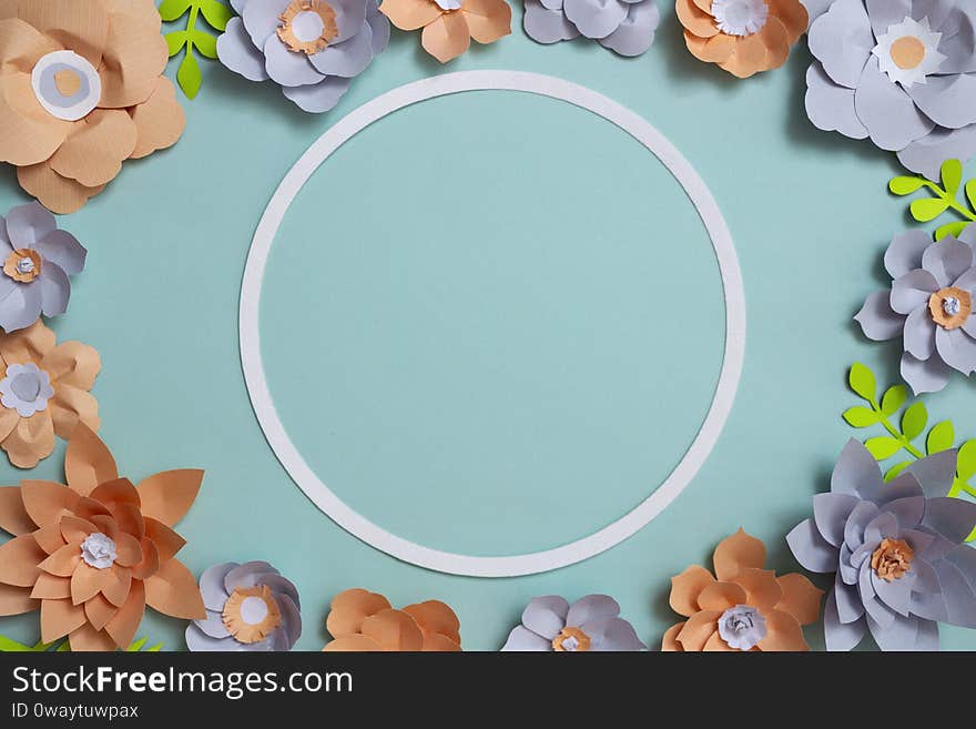 Flat lay of vintage round card frame, color paper flowers design on blue background. Top view, copy space, floral art,
