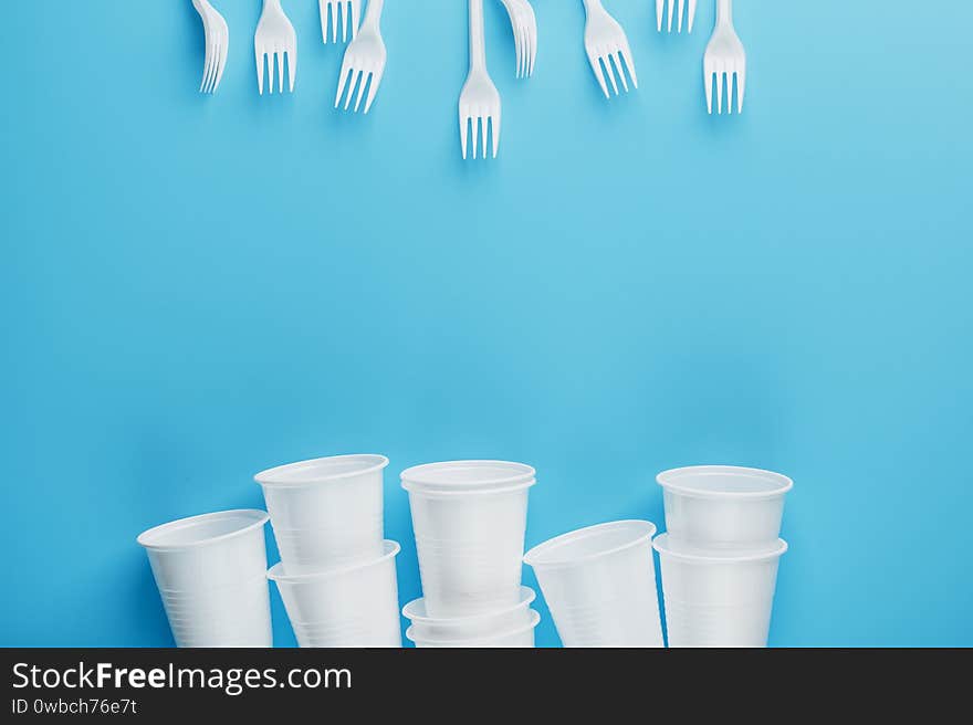 Dishes made of white plastic on a blue background. Free space. The view from the top