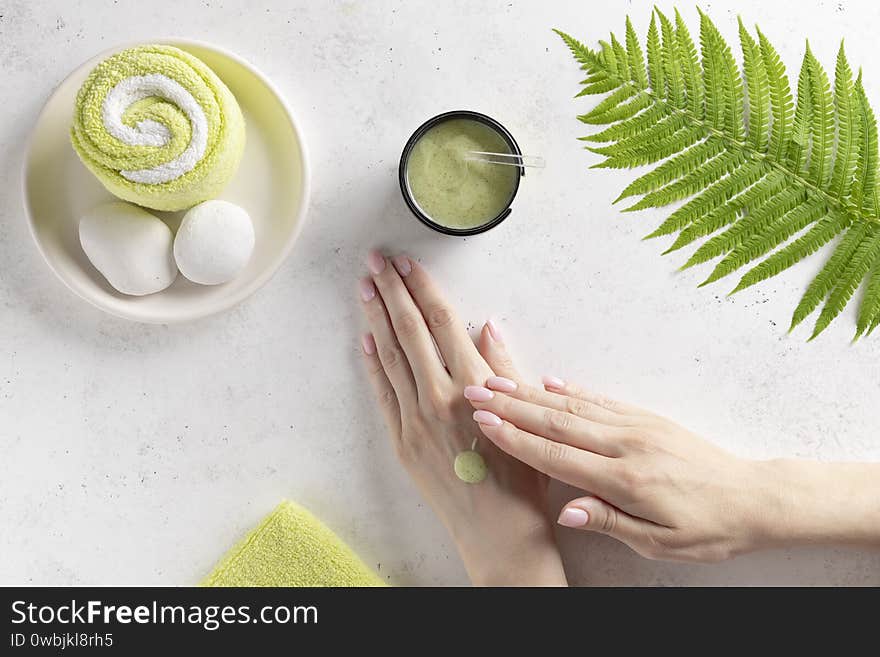 Beauty wellness spa treatment concept. woman smears a scrub on the arm. white concrete background. top view. copy space