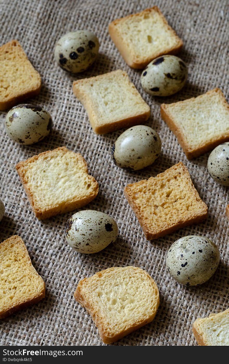 Ornament of square croutons and raw quail eggs on burlap